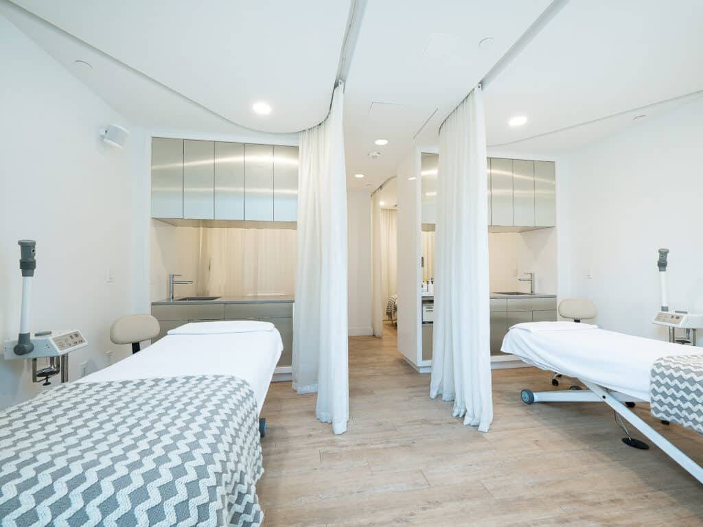 A shot of two of our treatment rooms in the DC Navy Yard location. everything is bright and clean, with nice medical beds and stainless steal cupboards