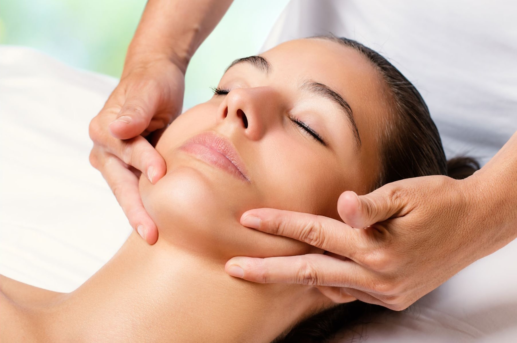 Woman on bed receiving a facial massage