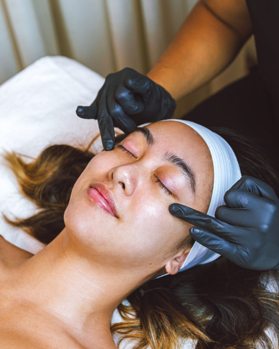 woman in a spa about to get her eyebrows threaded by an esthetician